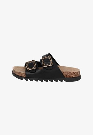 Zwarte schuifsandalen met twee overmaatse gouden accent kettinggespen, kurken voetbed en zwart rubberen zool met zaagtanden.