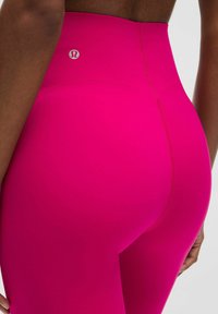 Magas derekú, élénk rózsaszín leggings sima, rugalmas anyagból, a derék részen logóval és hátsó varrásokkal.