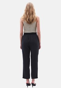 Gammalbeige stickad linne och svarta vida byxor. Byxorna har midja med dragsko och uppvikta nederdelar. Strukturerad, lättviktsmaterial.