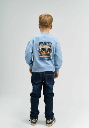 Lyseblå sweatshirt med en tegneseriehamburgergrafik og "WANTED" tekst på ryggen, parret med mørke jeans og sneakers.