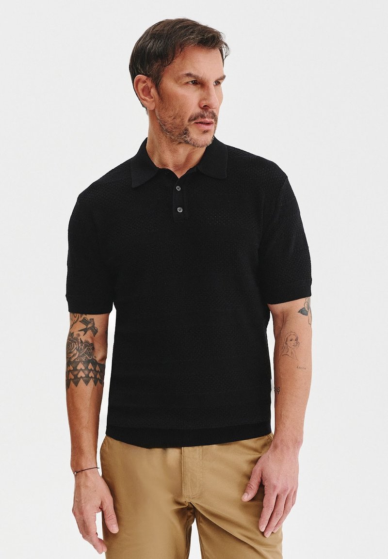 Czarna dzianinowa koszulka polo z kołnierzykiem, krótkimi rękawami i plisą na trzy guziki; charakteryzuje się strukturalną tkaniną i slim fit.