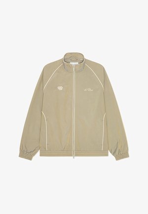 Μπεζ μπουφάν με ψηλό γιακά, φερμουάρ στο μπροστινό μέρος και λευκή διακοσμητική ραφή. Διαθέτει κέντημα με λογότυπο στο αριστερό στήθος και ελαστικά μανίκια.