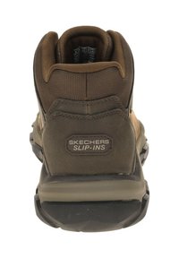 Brown Skechers Slip-Ins, featuring a textured upper, padded collar, and durable rubber sole, with branding on the heel.
