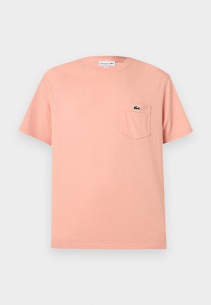 Svetloružové krátke bavlnené tričko s krátkym rukávom a náprsným vreckom, na ktorom je malý zelený krokodíl s logom.