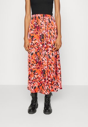 Person wearing a red, pink, and black patterned midi skirt with black lace-up combat boots and a black sleeveless top.