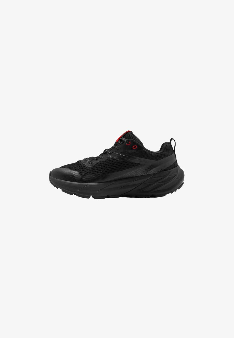 Chaussure de sport noire avec une tige en mesh, des accents rouges, une semelle texturée et un bout arrondi. Elle présente un design à lacets et un col rembourré.