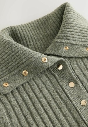 Grüner gerippter Strickkragen mit goldenen Druckknöpfen entlang der Vorderseite; der strukturierte Stoff mit vertikalen Streifen erhöht das visuelle Interesse.