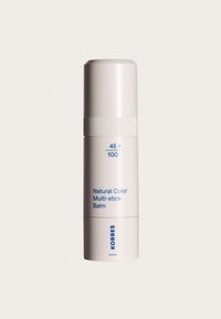 Balm stick cilindrico bianco con parte centrale rigata, etichettato "Balsamo Multi-stick Colore Naturale" e marchio "Korres" in testo blu su sfondo semplice.