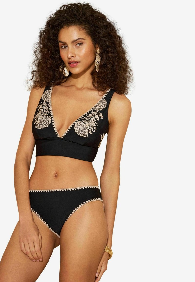 Ensemble bikini noir comprenant un haut à décolleté en V profond avec une broderie beige délicate et un bas taille haute assorti, orné d'une bordure en zigzag.