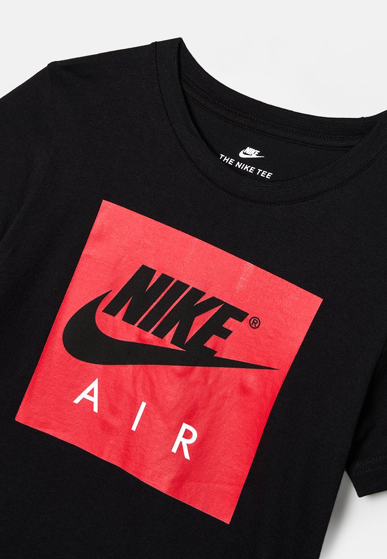 T-shirt en coton noir avec un graphique en carré rouge portant "NIKE" en noir et "AIR" en blanc, col rond et manches courtes standards.