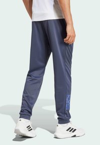 Pantalones deportivos navy fabricados con material liviano, que presentan un diseño ajustado, puños acanalados y una impresión de logo azul en el lado izquierdo.