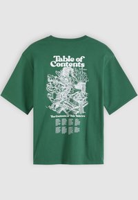 Camiseta de algodão verde com corte descontraído. Apresenta texto gráfico branco "Índice" e arte linear detalhada nas costas, listando os conteúdos.