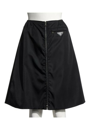 Jupe noire en forme trapèze avec fermeture éclair devant et petite poche zippée avec le logo Prada sur le côté droit de la ceinture.