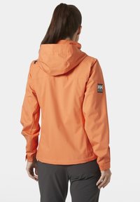 Oranje waterdichte jas met capuchon, met lange mouwen en een rechte snit. Details omvatten een logo-embleem op de linker schouder.