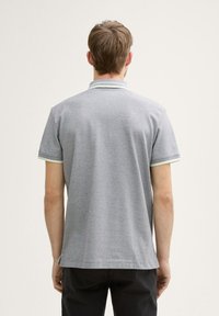 Graues Poloshirt aus strukturiertem Stoff, mit kontrastierendem Kragen und Ärmelbesatz. Kurzärmelig und mit geradem Saumdesign.