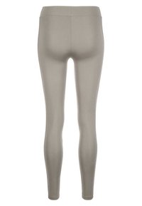 Leggings beige chiaro realizzati in tessuto elasticizzato, design aderente, con una texture liscia e una vita alta, che descrivono una silhouette snella e avvolgente.