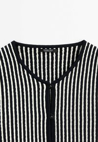 Cardigan en maille à rayures verticales noires et blanches avec un col rond et deux boutons noirs, étiqueté Massimo Dutti, fabriqué en Turquie.