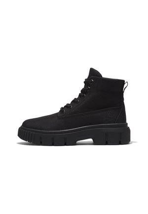 Botte montante noire à lacets avec semelle épaisse en caoutchouc et languette à l'arrière, présentant une tige en tissu texturé et un logo discret sur le côté.