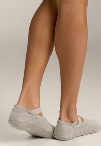 Sive gležnjače s teksturiranim pletenim uzorkom i elastičnim trakama oko gležnja. Imaju silikonski uzorak protuklizne podloge na đonu.