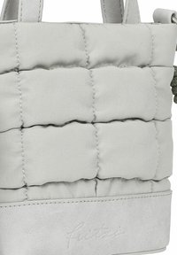 Borsa a tracolla grigia in tessuto trapuntato con base in pelle liscia, manici corti e logo in rilievo sottile sul fondo. Superficie texturizzata e design moderno.