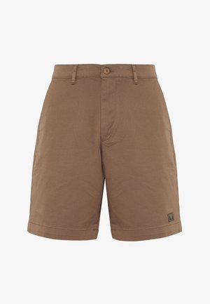 Shorts en coton marron avec une fermeture éclair, un bouton de fermeture et des poches latérales. Présente un petit écusson logo sur le côté gauche. Fini plat.