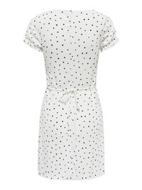 Robe blanche à manches courtes avec des pois noirs, taille cintrée nouée avec une ceinture, et tissu légèrement texturé.
