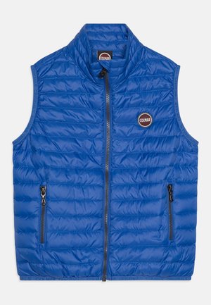 Gilet blu trapuntato con colletto alto, zip frontale e due tasche laterali. Presenta una toppa con logo circolare sul lato sinistro del petto. Materiale liscio e leggero.