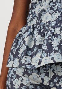 Sinine lilleline peplum-särk helesiniste rooside mustriga. Omab volangiga äärt ja struktureeritud rinda. Tekstuuriga teksakanga välimus.