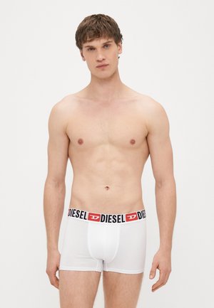 Fehér pamut boxerrövidnadrág fekete és piros "DIESEL" logós derékszíjjal, testhezálló fazonban és sima textúrával. Férfi modellen viselve.