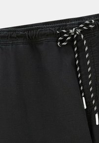 Shorts noirs avec une taille élastique et un cordon de serrage. Le cordon est noir avec des rayures blanches et possède des embouts en plastique.