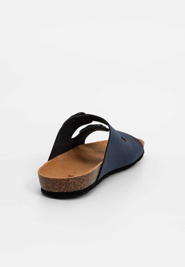 Sandale noire avec deux larges brides, semelle en liège et semelle en caoutchouc texturé. Design ouvert à l'arrière avec un profil minimaliste et des détails découpés.