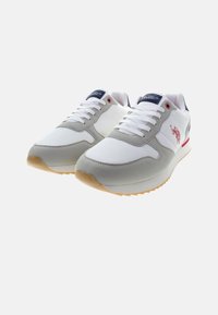 Scarpe da ginnastica atletiche con una tomaia in rete bianca e suede grigio, suola in gomma e dettagli rossi e blu. Presentano lacci bianchi e branding sulla linguetta.