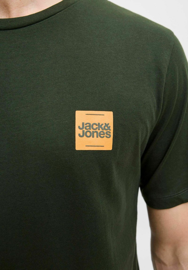 Tmavě zelené bavlněné tričko s čtvercovou oranžovou nášivkou se textem "Jack & Jones", kulatým výstřihem a krátkými rukávy.