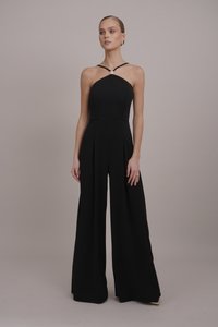 Giubbotto nero con corpino aderente, scollo all'americana e pantaloni a gamba larga. Presenta pince in vita e un accentuato hardware decorativo.
