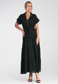Czarna maxi sukienka z krótkimi rękawami, z przodu na guziki i wiązaniem w talii. Posiada warstwowe falbany i płynny krój. Gładka tekstura tkaniny.