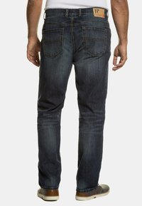 Vaqueros de mezclilla azul oscuro con corte recto, que cuentan con dos bolsillos traseros, un sutil detalle de costura y un parche de cuero con la marca en la cintura.