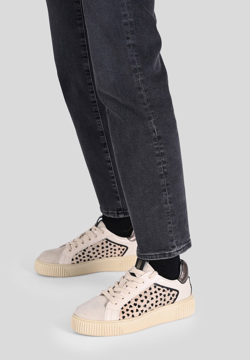 Sneakers lace-up di colore chiaro realizzati in suede e mesh, con un motivo a cuori neri sui lati e una suola in gomma testurizzata color crema.