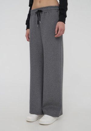 Pantaloni della tuta grigi a gamba larga con vita elastica e cordino. Il tessuto sembra morbido e comodo, con una consistenza liscia.
