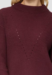 Bordeaux gebreide trui met een hoge ribbelkraag, featuring een V-vormig detail met kleine uitsparingen en een gestructureerde stof.