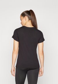 Svart kortermet t-skjorte laget av myk stoff, med rund hals og en figurnær design, sett fra baksiden.
