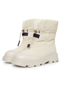 Botas de invierno acolchadas en beige con puntera redondeada, suela de goma gruesa y cordón ajustable. Presentan acentos de marca en negro en la parte frontal.