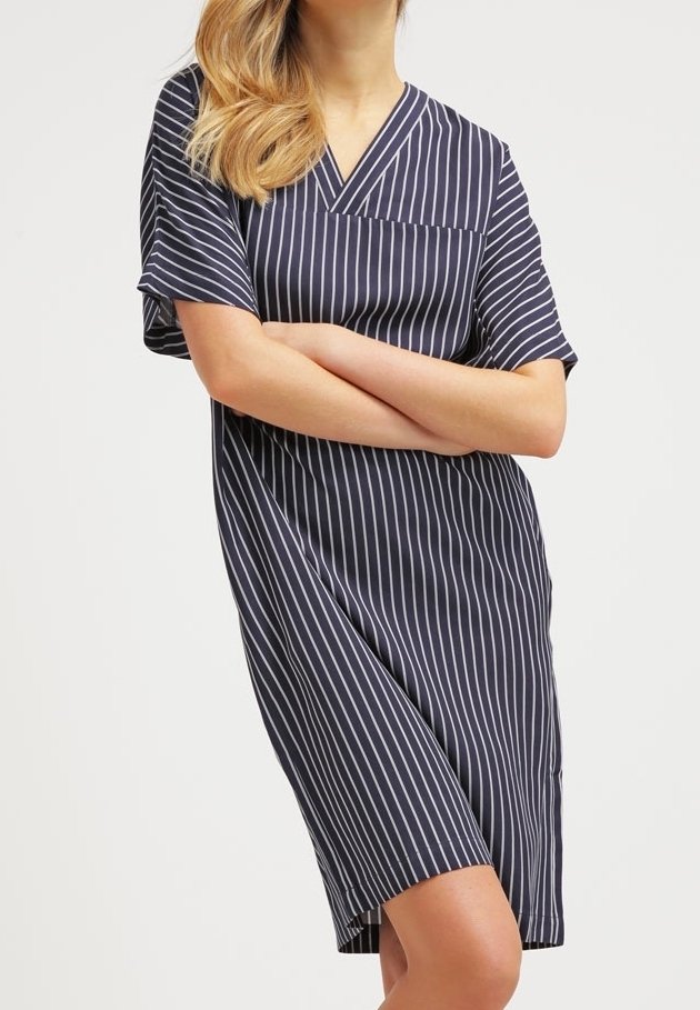 Robe courte rayée marine avec un décolleté en V, des manches courtes et une poche poitrine. Fabriquée en tissu léger avec une texture douce.