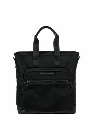 Sac fourre-tout noir en tissu durable avec deux poignées supérieures, une poche zippée à l'avant et un fond lisse. Présente un branding minimaliste.