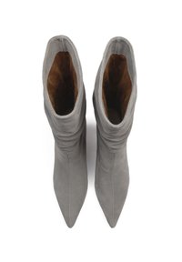 Bottes de cheville en suède gris avec un bout pointu et un design froncé. L'intérieur présente une doublure marron. Semelle plate sans quincaillerie visible.