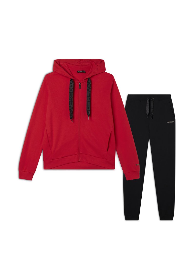 Felpa rossa con zip e cappuccio, con lacci e polsini neri, abbinata a pantaloni della tuta neri con un accento di logo. Entrambi realizzati in tessuto morbido.