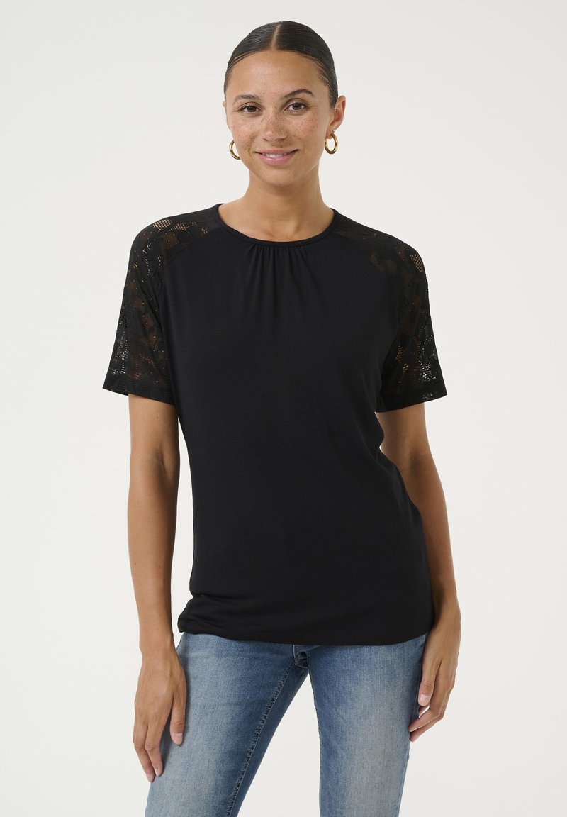 Melns T-kreklis ar mežģīņu piedurknēm, apaļu kakla izgriezumu, brīvu piegriezumu un mīkstu audumu. Piedurknes ir ar ziedu mežģīņu rakstu, kas piešķir papildus detalizāciju.