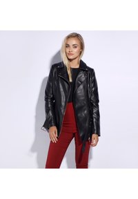 Black leather biker jacket with asymmetrical zipper, snap details, and side pockets. Worn over a black top and red pants. Smooth texture.