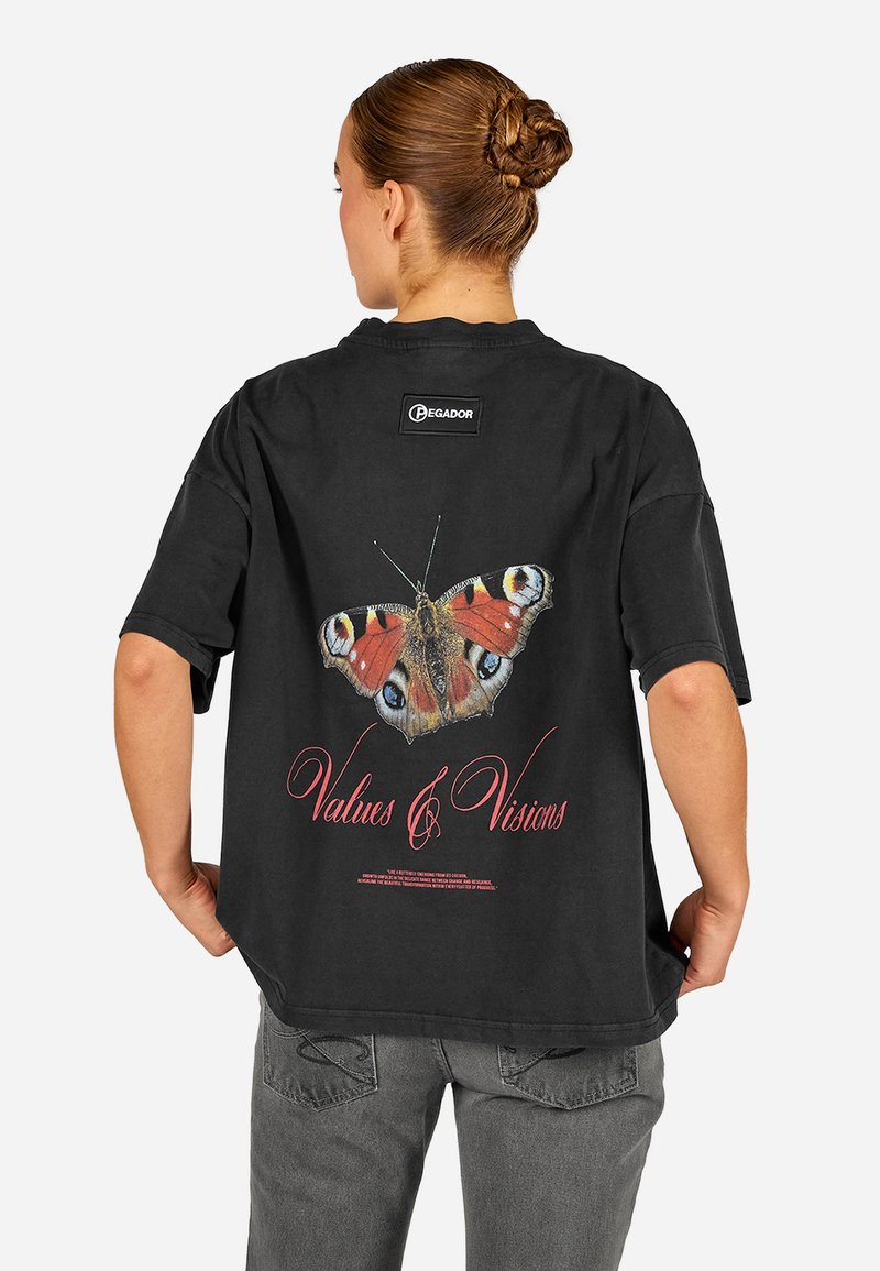 Svart oversized t-skjorte med et fargerikt sommerfugl-grafikk på ryggen, med teksten "Verdier & Visjoner" i rødt under.
