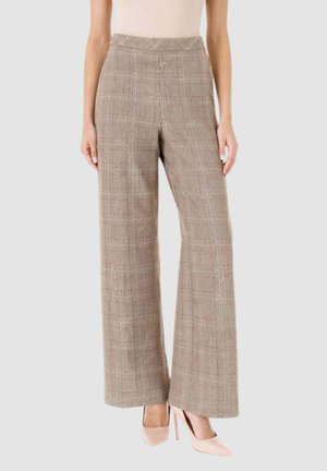 Pantaloni beige a vita alta a gamba larga con stampa scozzese, indossati con décolleté a punta beige chiaro, mostrati su una persona in piedi su sfondo chiaro.