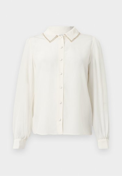 Blouse blanche à manches longues avec col, accent texturé doré sur le col et fermeture à boutons sur le devant. Tissu doux et lisse.